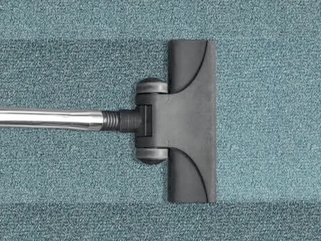 A vacuum head being drawn across commercial carpet